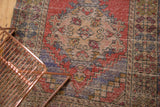 Vintage distressed Oushak runner detail, showing faded red, blue, and ivory geometric motifs.