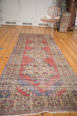 Distressed pile texture and faded red, blue corner spandrel on a vintage Oushak runner.