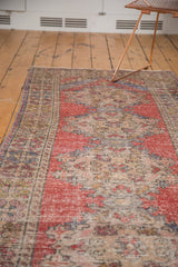 Distressed Oushak runner with faded red, blue, and ivory repeating traditional motifs.