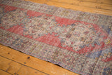Hand-knotted vintage Oushak runner showcasing distressed pile, repeating medallions, and faded red.