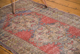 Distressed Turkish Oushak runner pile with faded cherry red, blue, and ivory motifs.