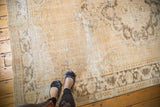 Vintage distressed Oushak carpet with even wear, exposed foundation, and coffee brown border.