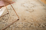 Distressed Oushak carpet detail, showing scalloped medallion, vine border, antique ivory and coffee brown.
