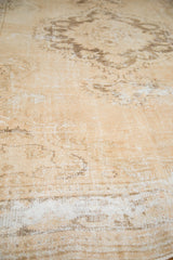 Distressed vintage Oushak carpet texture showing exposed foundation with antique ivory and brown tones.