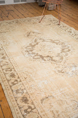 Distressed vintage Oushak rug texture detail, showcasing ivory pile with coffee brown meandering vine border.