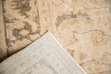 Distressed Oushak pile texture in ivory and coffee brown, exposing its hand-knotted foundation.