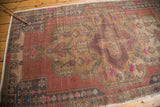 Distressed Oushak rug corner, showing faded blush, gold, and pink geometric details.