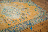Distressed gold Oushak rug corner with brilliant blue and mint green floral motifs.