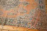 Distressed vintage Oushak carpet showcasing worn pile in dusty peach and faded blue tones.