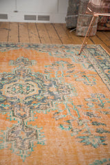 Distressed texture of vintage Oushak rug, faded peach, blue, and mint green floral motifs.