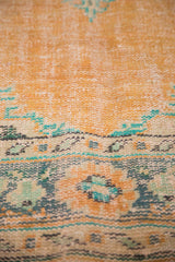 Dusty peach distressed Oushak carpet, showing mint green and faded blue floral details.