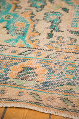 Faded apricot, blue, and ivory distressed Oushak rug texture and border detail.