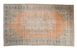 Vintage Distressed Oushak carpet, faded peach field, royal blue borders, subtle floral medallion.