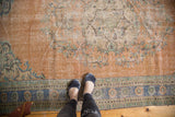 Distressed vintage Oushak rug with faded apricot field, blue border, and visible foundation wear.