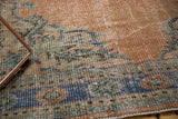 Distressed pile of vintage Oushak rug, revealing faded blue, peach, and mint green patterns.