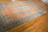 Distressed vintage Oushak rug corner, showing peach field and royal blue floral border.