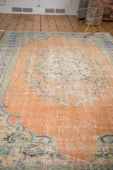 Distressed vintage Oushak carpet: worn dusty peach apricot pile, faded floral patterns.