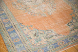 Distressed vintage Oushak rug corner with faded apricot field, mint floral details, and faded royal blue border.