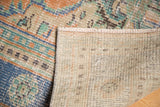 Distressed vintage Oushak pile, exposed foundation, visible hand-knotted rug back and fringe.