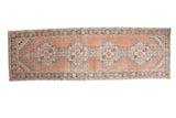 Distressed Oushak runner, apricot field, repeating ivory medallions, pink-grey stepped spandrels.