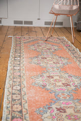 Distressed Oushak runner with faded apricot field, showcasing vibrant pink and ivory medallion motifs.