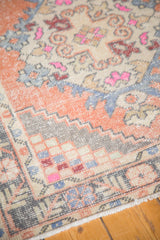 Distressed vintage Oushak runner corner with worn pile and apricot stepped check spandrels.