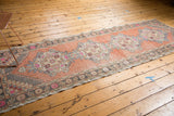 Distressed Oushak runner corner with faded apricot field, stepped spandrels, and geometric border.