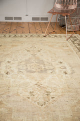 Distressed vintage Oushak pile with muted ivory, sand, charcoal tones, visible foundation.