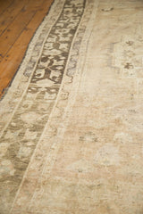 Distressed Oushak carpet showing stylized dark border and low beige pile texture.