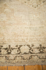 Distressed Oushak rug detail showing charcoal border pattern, worn beige pile, and fringe.