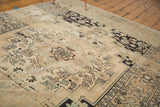Vintage distressed Oushak carpet corner with abrashes, ivory, sand, charcoal, and pale pistachio motifs.