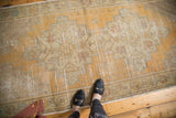 Distressed vintage Oushak runner featuring saffron gold field, serrated geometric medallion, and muted corner spandrels.