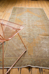 Distressed vintage Oushak runner showing worn saffron gold field and patterned border with visible foundation.