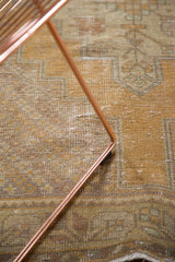 Distressed Oushak rug, close-up with saffron yellow field, serrated pattern, and visible foundation.