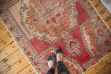 Distressed vintage Oushak rug detail with rococo stylization, germinating plant motif, and deep red border.