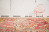 Distressed Oushak rug showing rococo medallion, germinating plant motif, and vibrant abrash.