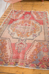 Distressed vintage Oushak rug with prominent abrash, faded blush, red, and gold rococo designs.