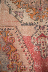 Even wear and abrash on distressed Oushak rug, with rococo patterns in blush, gold, and red.