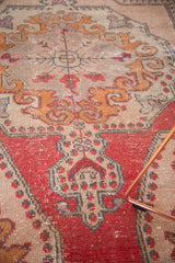 Distressed vintage Oushak rug with worn rococo flare and germinating plant motif in red and beige tones.