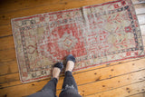 Faded cherry red and ivory distressed Oushak runner with geometric medallion.
