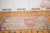 Distressed Oushak rug runner with faded cherry red, antique ivory, and geometric plant motifs.