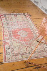 Worn pile of vintage Oushak runner with faded cherry red, ivory, and charcoal patterns.