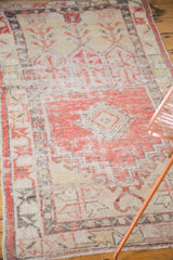 Distressed Oushak runner corner with faded cherry red, ivory, charcoal geometric wear.