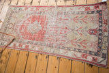 Distressed vintage Oushak runner with unique asymmetric pattern in faded red and ivory.