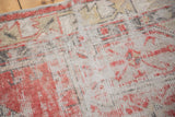 Distressed Oushak rug showing faded red and charcoal patterns with exposed foundation.