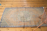 Distressed vintage Turkish Oushak rug's peach field, faded blue border, visible light foundation.