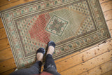 Distressed vintage Oushak rug with abrupt abrash, brick red field, and muted green accents.
