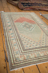 Vintage distressed Oushak rug showing abrash and geometric motifs in brick red, ivory, and mint.