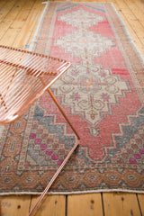 Vintage Oushak runner's distressed pattern, showing blush, charcoal, and fuchsia stepped diamonds.
