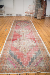 Vintage Oushak runner's distressed texture, stepped diamond pattern, blush, red, beige, charcoal hues.